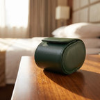 Étui de voyage Escale vert foncé fermé, posé sur une table de chevet dans une chambre d’hôtel