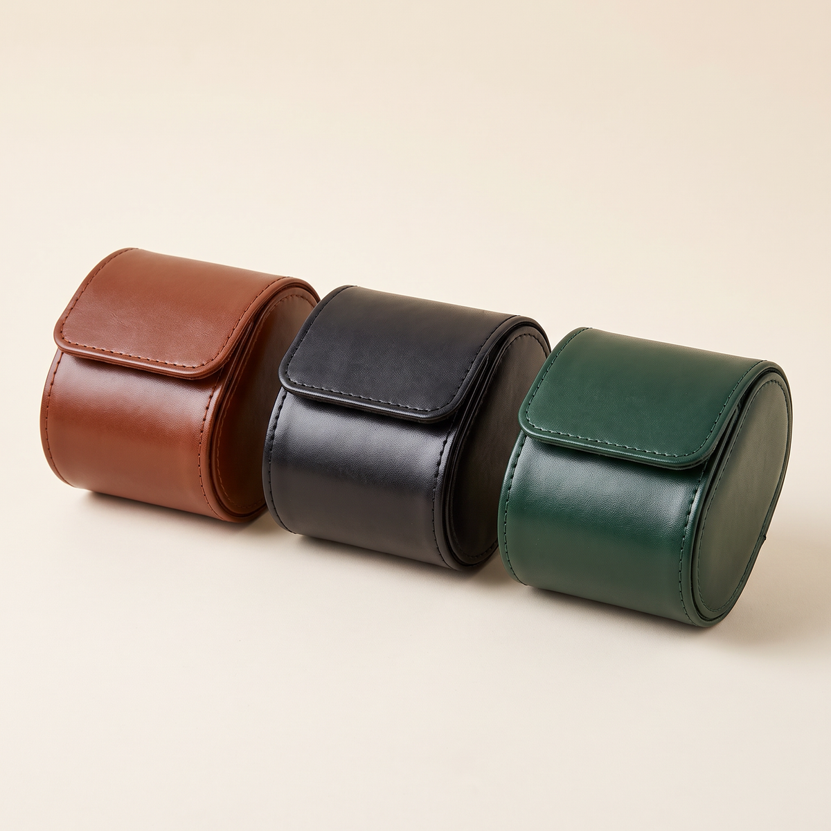 Les trois coloris de l’étui de voyage Escale côte à côte : cognac, noir et vert foncé, fermés